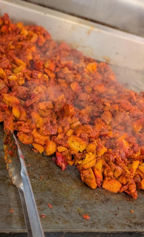 Spiced chicken cooking on the flat top grill